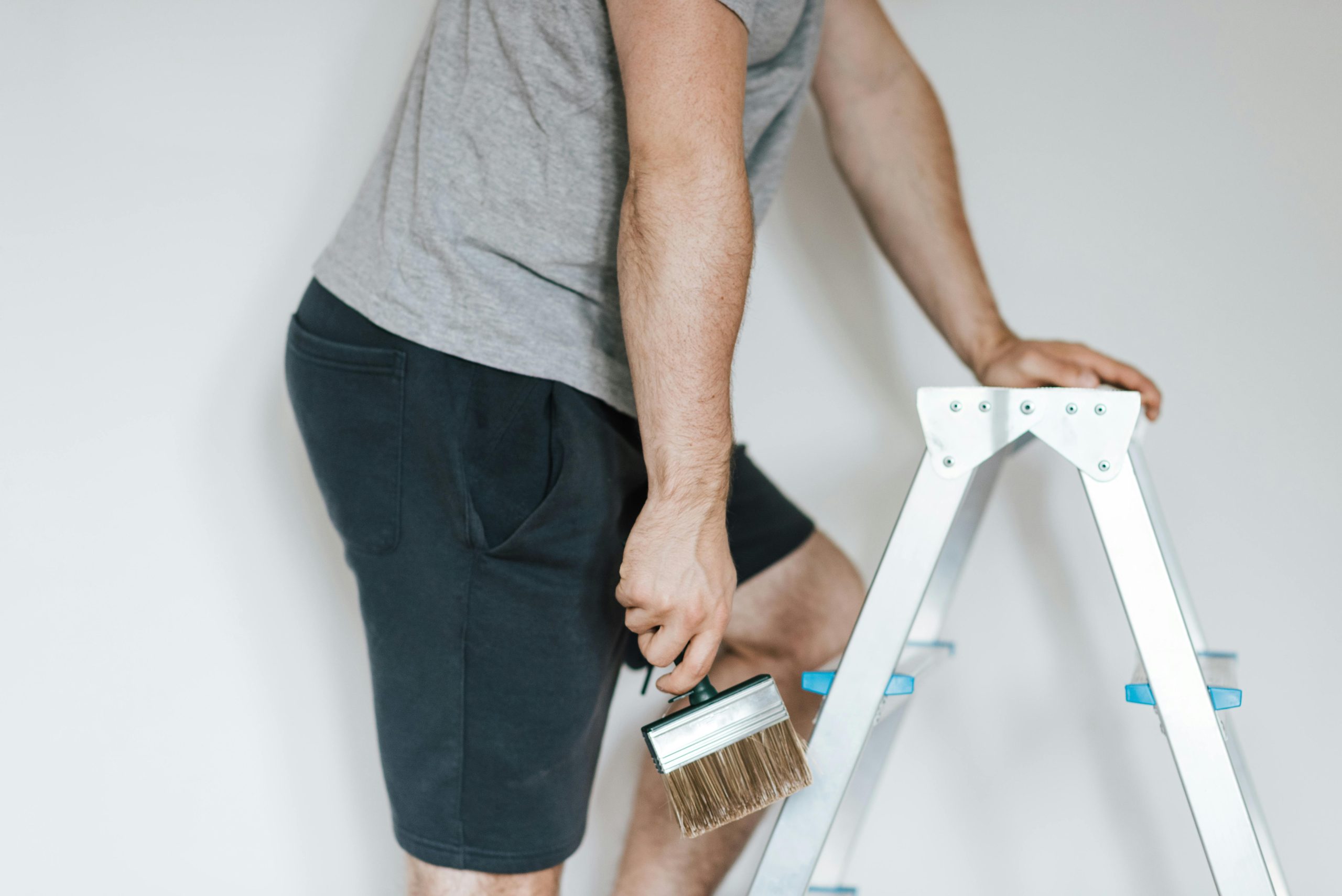 man on a ladder holding a paintbrush